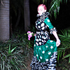 Madonna with pink hair, posing with pink flowers in a green dress.